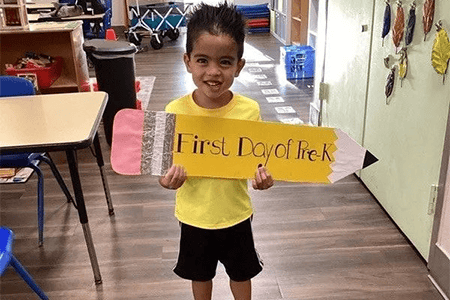 Child holding first day of pre k sign