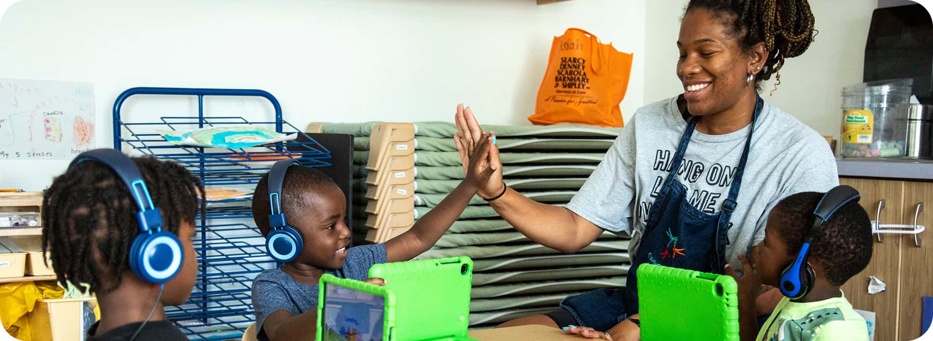 Children using tablets with a teacher in a classroom setting.