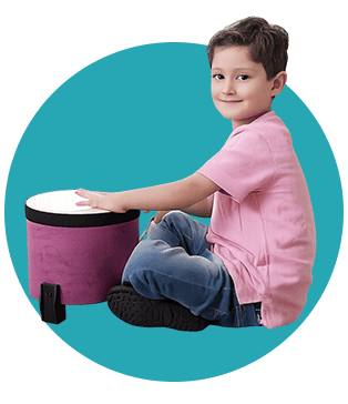 Young boy sitting and playing a purple musical drum with a smile.
