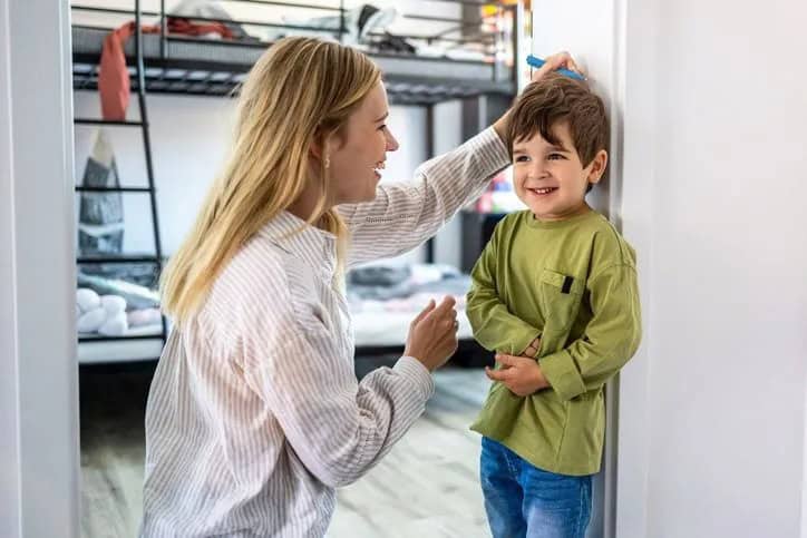 parent measuring child against wall
