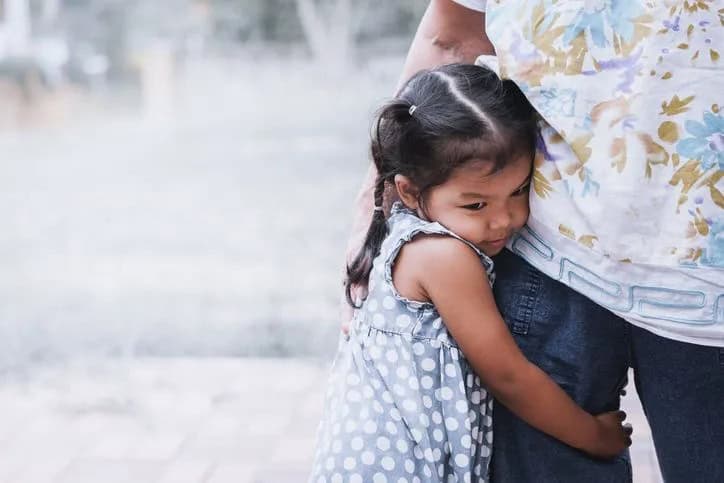 child hugging adult leg